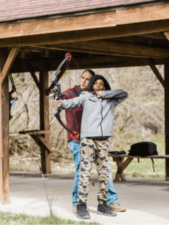 Girl learning to shoot bow and arrow 