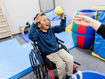 A boy, Danylo, in a wheelchair with hands extended in joy